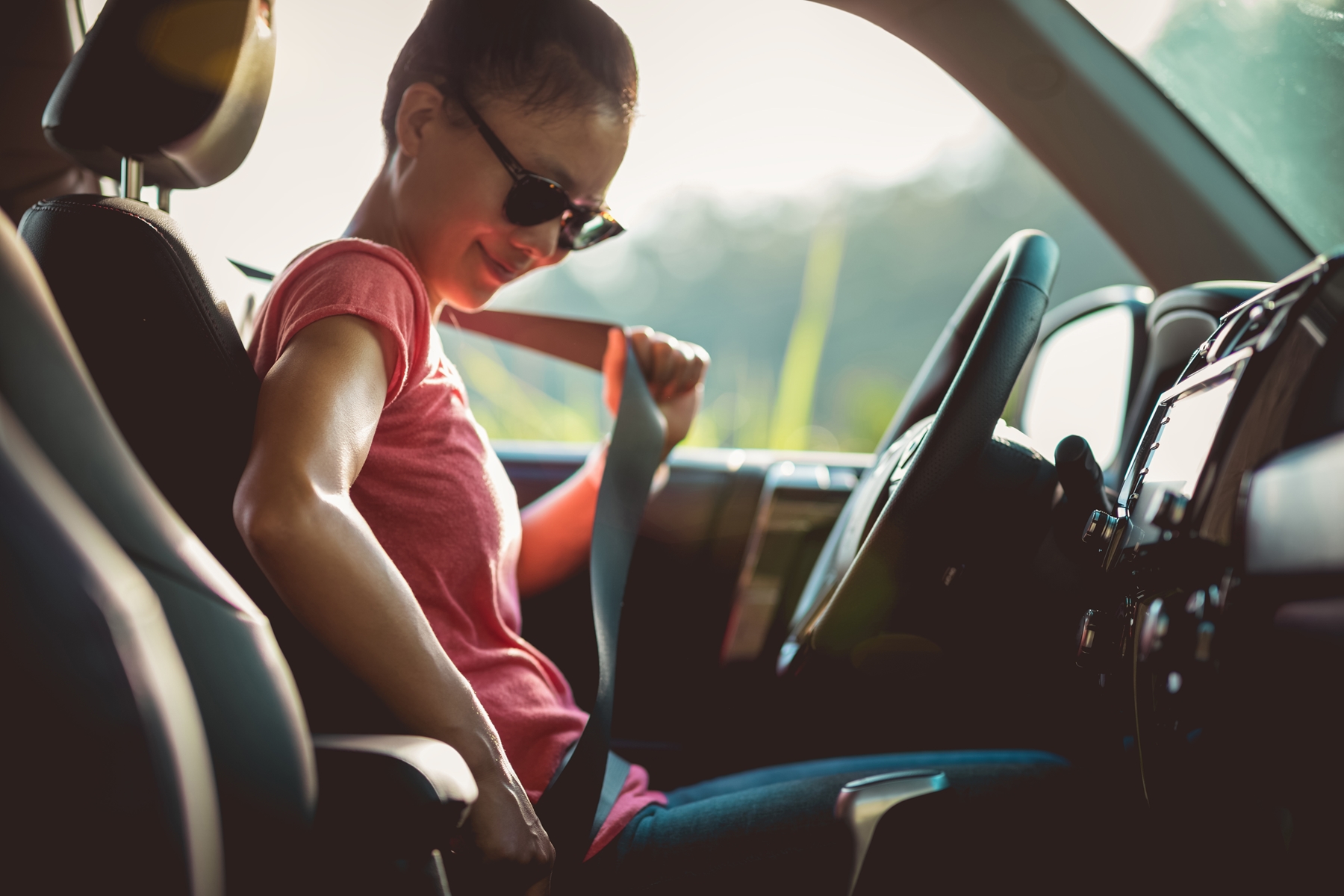 Woman unbuckling a seat belt in her car